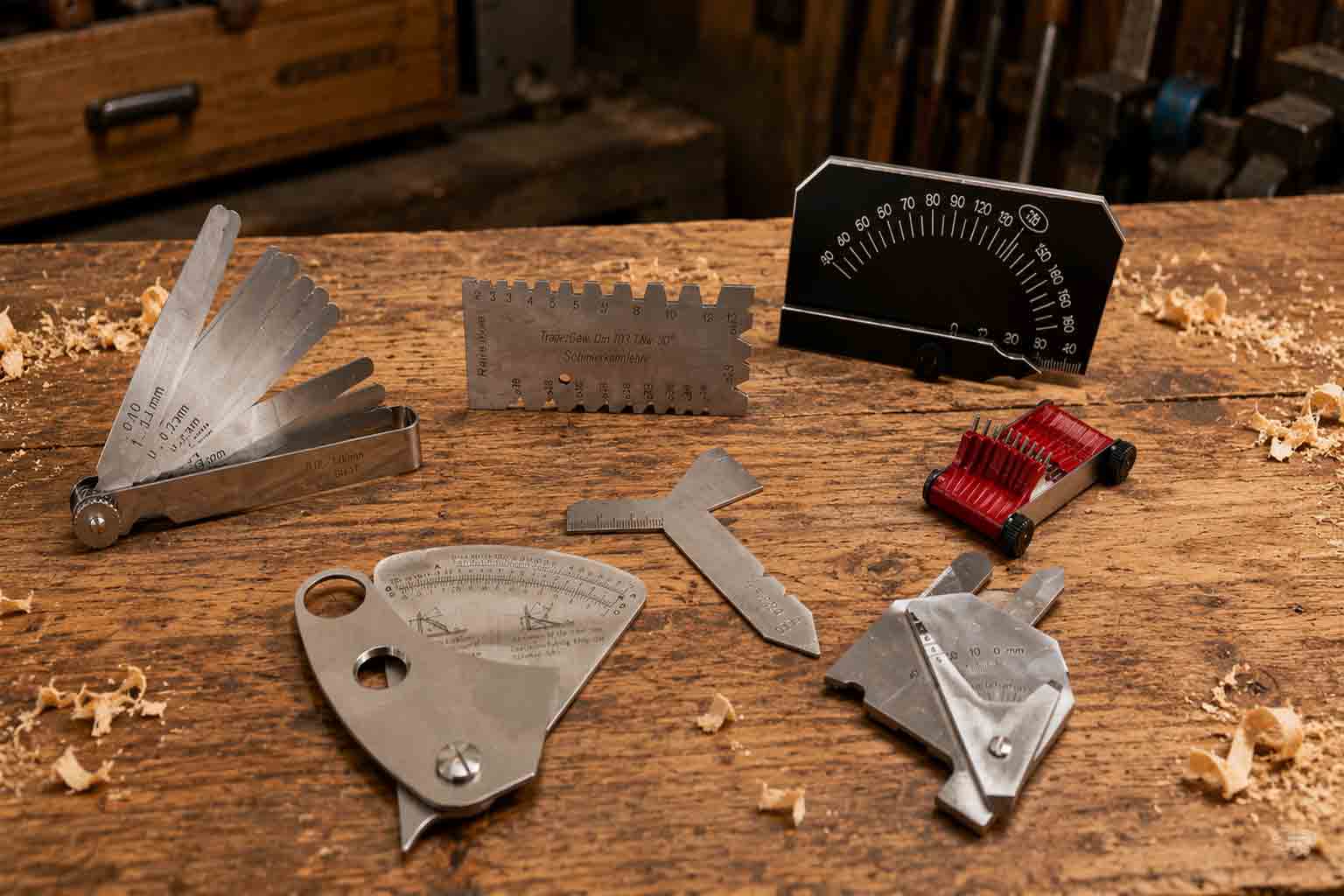 Prüflehren auf einer Werkbank – Fühlerlehren, Schweißnahtlehren, Messkeile & Bohrerlehren und weitere Mess- und Prüflehren für Werkstatt, Metallbearbeitung und Handwerk.